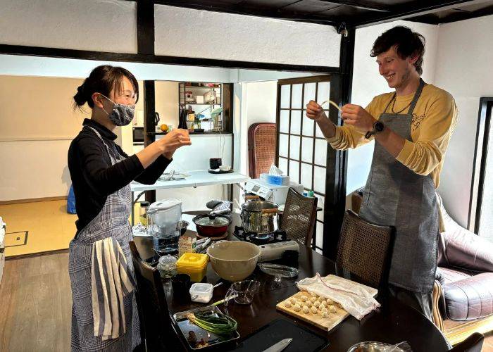 A smiling guest being shown how to make Beppu noodles in a cooking class.